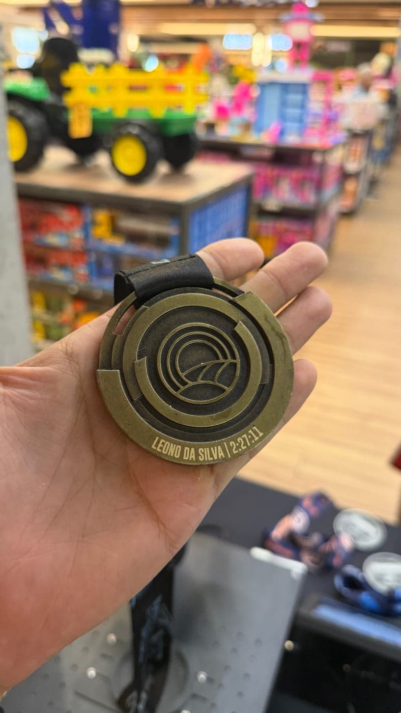 Medalha do desafio com nome e tempo gravados acompanhando a curva da borda